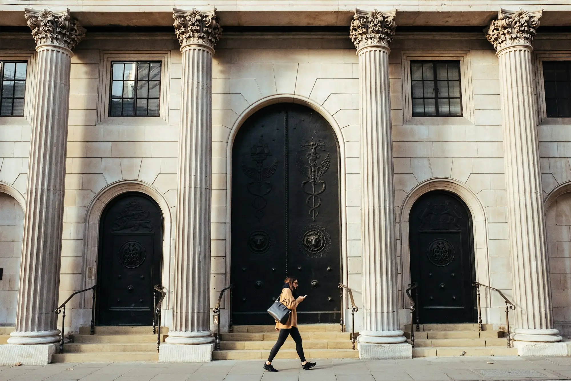 Person walking past a white building with tall columns
